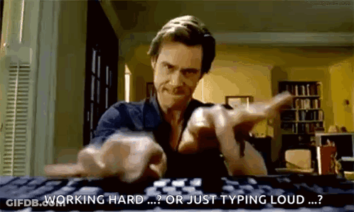 A Man Is Typing On A Computer Keyboard And Pointing At The Camera . GIF