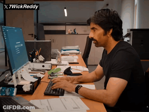 A Man Is Typing On A Keyboard In Front Of A Computer And A Sign That Says X7wick Reddy GIF