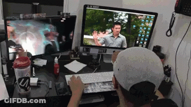 A Man Is Typing On A Keyboard In Front Of Two Computer Monitors One Of Which Says ' A ' On It GIF