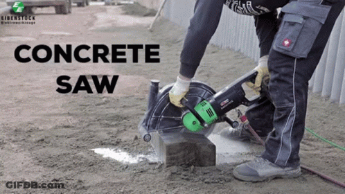 A Man Is Using A Concrete Saw To Cut A Concrete Block GIF
