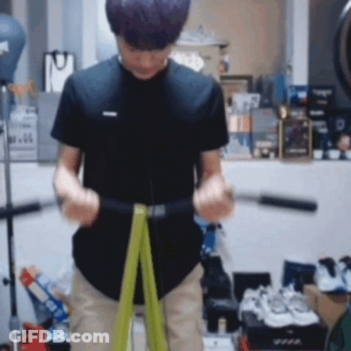 A Man Is Using A Green Resistance Band To Exercise . GIF