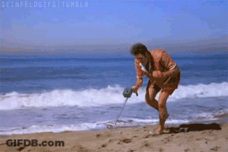 A Man Is Using A Metal Detector To Search For Something On The Beach . GIF