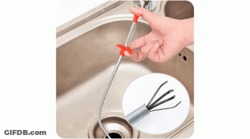 A Man Is Using A Milwaukee Drain Cleaner To Clear A Drain Under A Sink GIF