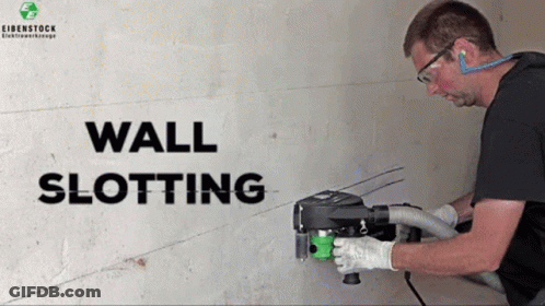 A Man Is Using A Wall Slotting Machine To Cut Holes In A Wall GIF