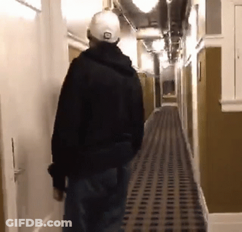A Man Is Walking Down A Hallway Wearing A Hat That Says Lg On It GIF