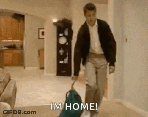 A Man Is Walking Down A Hallway With A Suitcase And A Dog And Says I 'M Home . GIF