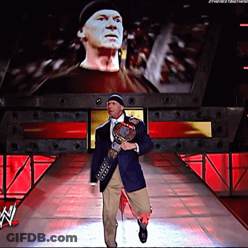 A Man Is Walking Down A Ramp Holding A Wrestling Trophy GIF