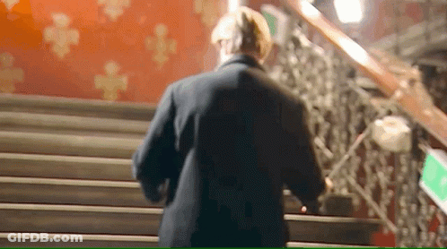 A Man Is Walking Down A Set Of Stairs . GIF