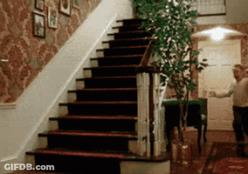A Man Is Walking Down A Set Of Stairs In A Hallway GIF