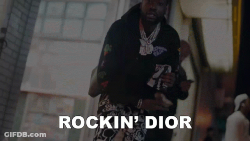 A Man Is Walking Down A Street And The Words Rockin ' Dior Are On The Bottom GIF