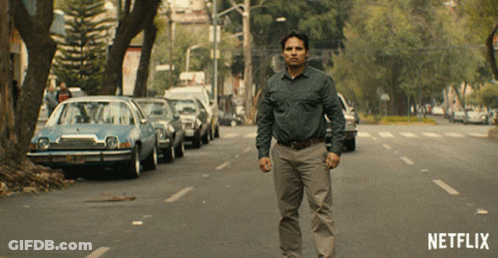A Man Is Walking Down A Street With A Netflix Logo In The Corner GIF