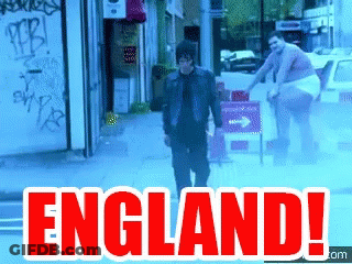 A Man Is Walking Down A Street With The Words England Written In Red GIF