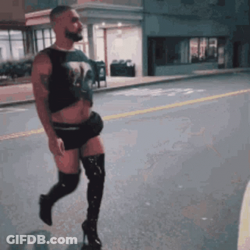 A Man Is Walking Down The Street Wearing Thigh High Boots GIF