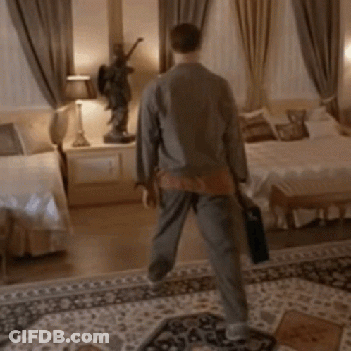 A Man Is Walking In A Bedroom With A Statue Of An Angel On The Wall GIF