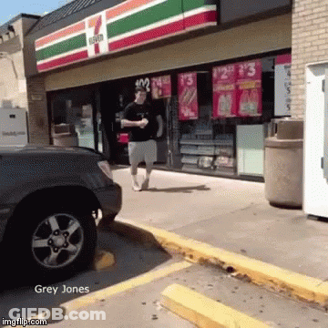 A Man Is Walking In Front Of A 7 Eleven GIF
