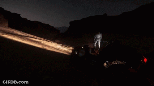 A Man Is Walking In The Dark With A Flashlight GIF
