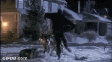 A Man Is Walking In The Snow With A Dog . GIF
