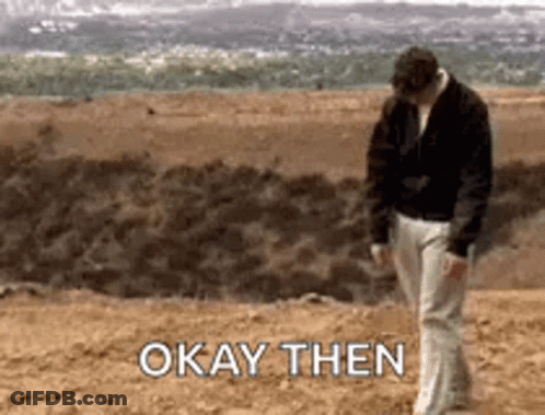 A Man Is Walking On A Dirt Field With The Words `` Okay Then '' Written On The Ground . GIF
