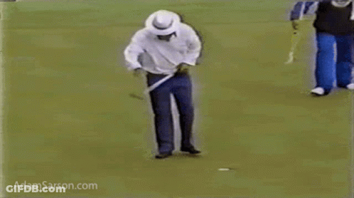A Man Is Walking On A Golf Course Holding A Golf Club . GIF