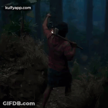 A Man Is Walking Through A Dark Forest With A Lantern . GIF