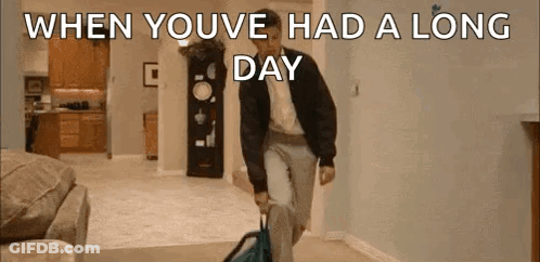 A Man Is Walking Through A Living Room Carrying A Suitcase And A Backpack . GIF