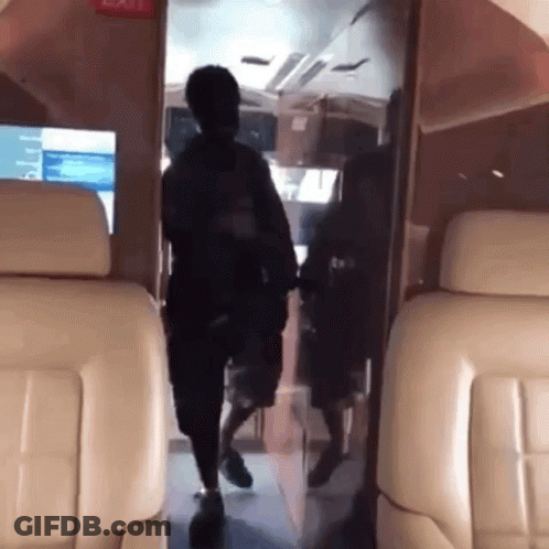 A Man Is Walking Through The Door Of A Plane GIF