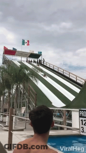 A Man Is Watching A Person Slide Down A Water Slide At A Water Park With The Words Viralhog On The Bottom GIF