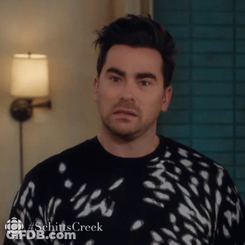 A Man Is Wearing A Black And White Sweater With The Word Schitts Creek On The Bottom GIF