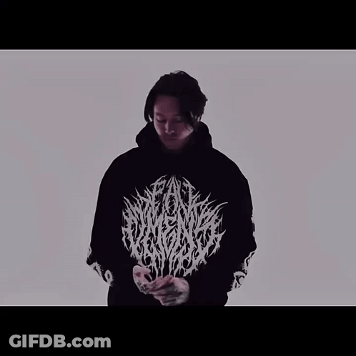 A Man Is Wearing A Black Hoodie With A White Logo On The Front GIF