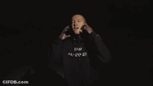 A Man Is Wearing A Black Hoodie With Korean Writing On The Front GIF