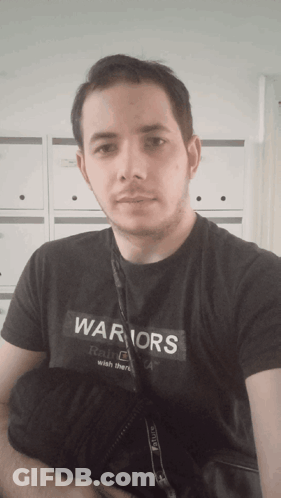 A Man Is Wearing A Black Shirt That Says Warriors On It GIF