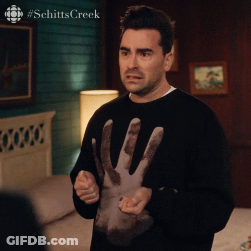 A Man Is Wearing A Black Sweater With A Hand On It And The Words Schitts Creek On The Bottom GIF