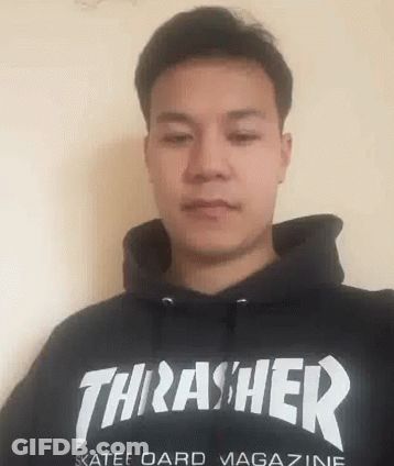 A Man Is Wearing A Black Thrasher Hoodie And Looking At The Camera . GIF