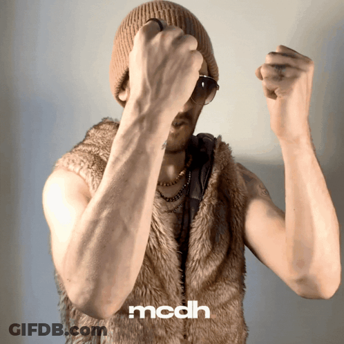 A Man Is Wearing A Fur Vest And A Beanie And The Word Mcdh Is On The Bottom Right GIF