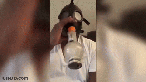 A Man Is Wearing A Gas Mask And Smoking A Bong . GIF