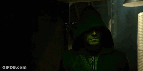 A Man Is Wearing A Green Hooded Jacket And Holding An Arrow . GIF