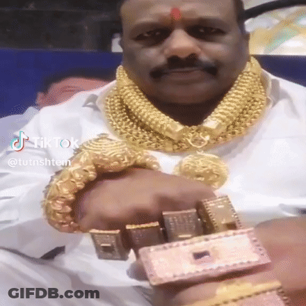 A Man Is Wearing A Lot Of Gold Jewelry Including A Gold Necklace And Bracelets . GIF