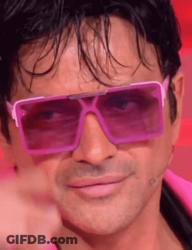 A Man Is Wearing A Pair Of Pink Sunglasses And Pointing At The Camera . GIF