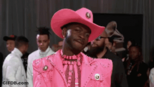 A Man Is Wearing A Pink Cowboy Hat And A Pink Jacket GIF