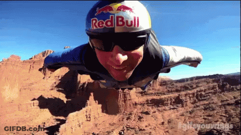A Man Is Wearing A Red Bull Helmet And Sunglasses GIF