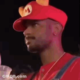 A Man Is Wearing A Red Hat With Ears On It And A Mushroom On It . GIF