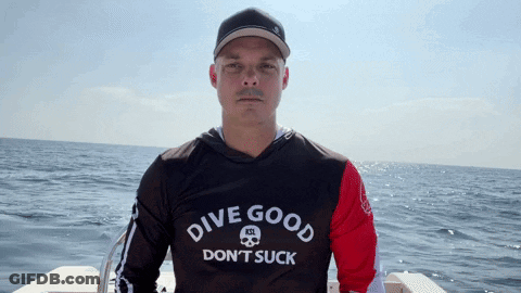 A Man Is Wearing A Shirt That Says Dive Good Don 'T Suck GIF