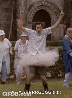 A Man Is Wearing A Tutu And Dancing In A Park . GIF