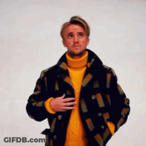 A Man Is Wearing A Yellow Turtleneck Sweater And A Plaid Jacket . GIF