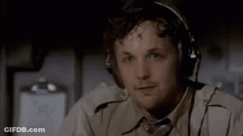 A Man Is Wearing Headphones And A Tie While Sitting On An Airplane . GIF