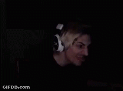 A Man Is Wearing Headphones In The Dark And Smiling . GIF