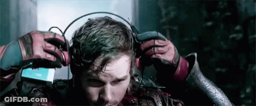 A Man Is Wearing Headphones On His Head While Standing In A Dark Room . GIF