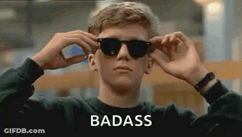 A Man Is Wearing Sunglasses And The Word Badass Is On The Bottom . GIF
