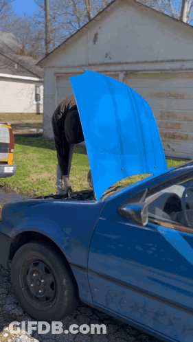 A Man Is Working On A Blue Car With The Hood Up GIF
