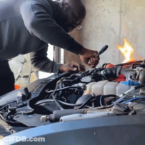 A Man Is Working On A Car Engine With A Wrench GIF